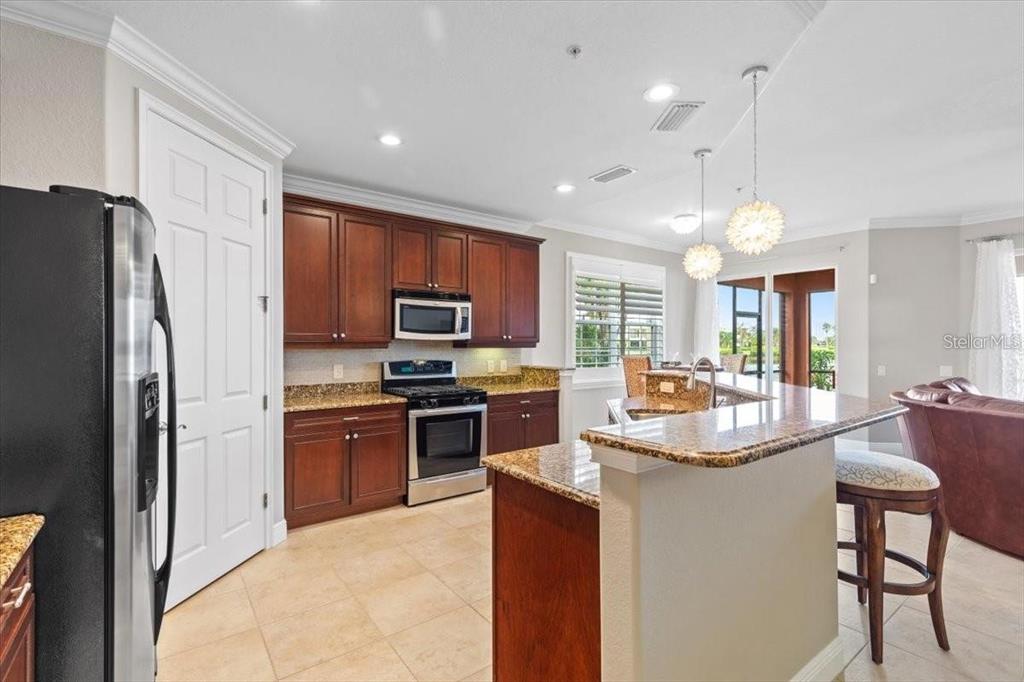 1143 Riverscape Street, Unit A Bradenton, FL 34208 - Photo 11 of 53 a kitchen with stainless steel appliances granite countertop a refrigerator a stove a sink a stove a dining table and chairs
