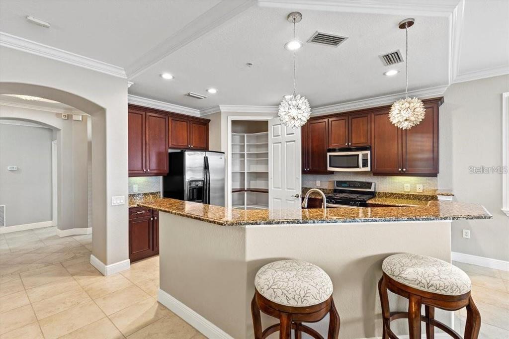 1143 Riverscape Street, Unit A Bradenton, FL 34208 - Photo 14 of 53 a kitchen with stainless steel appliances granite countertop a refrigerator a stove a sink a oven with a dining table and chairs
