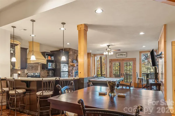 a kitchen with stainless steel appliances kitchen island granite countertop a stove a refrigerator a sink a dining table and chairs with wooden floor