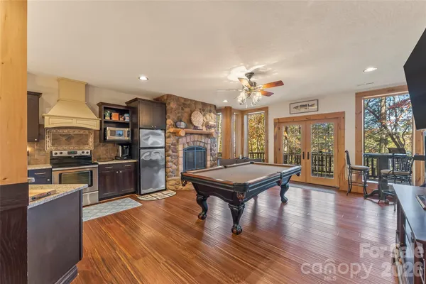 a living room with stainless steel appliances furniture a fireplace and a window