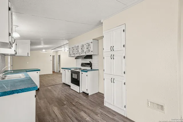 a kitchen with granite countertop a refrigerator stove top oven and sink