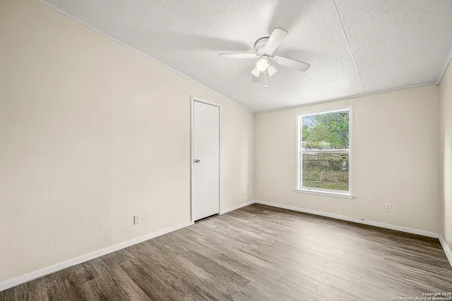 an empty room with wooden floor fan and windows