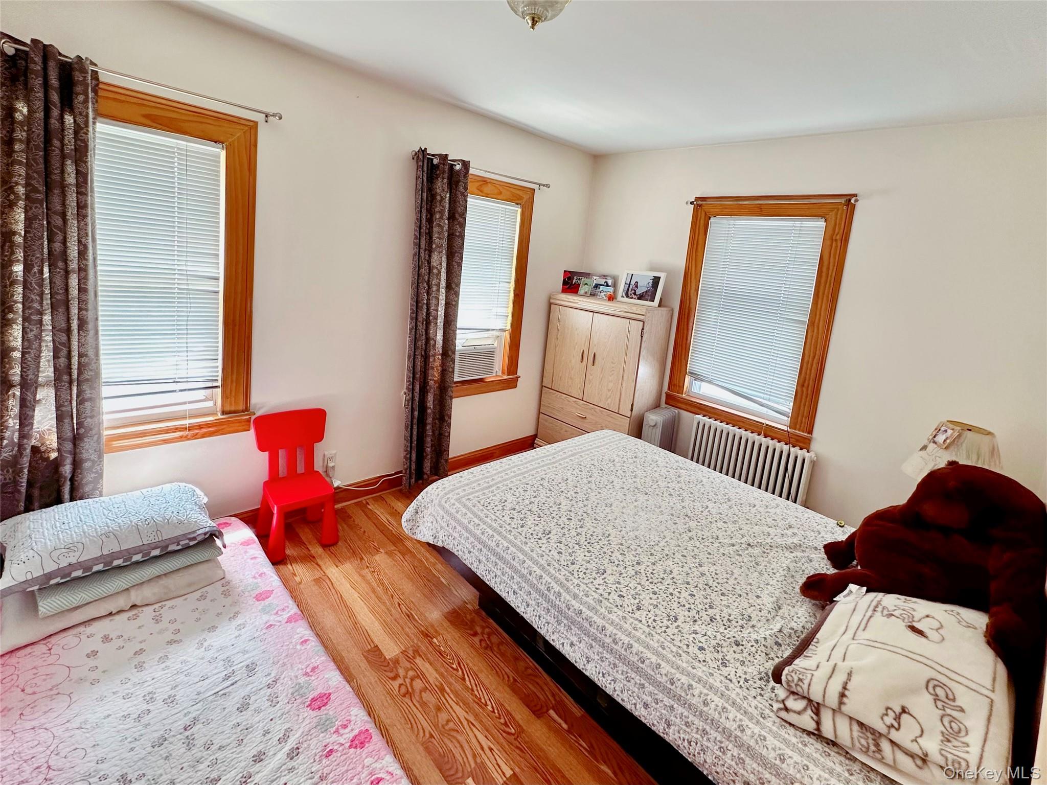 90-11 75th Street Queens, NY 11421 - Photo 4 of 9 a bedroom with a bed and wooden floor