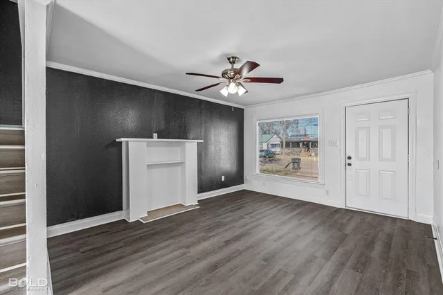 a view of an empty room with wooden floor and a ceiling fan