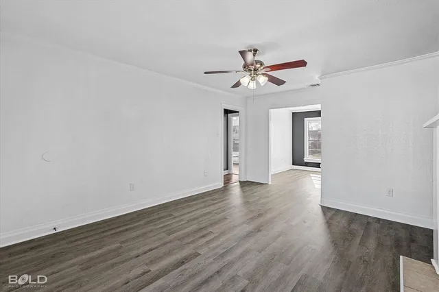 a view of an empty room with window and wooden floor