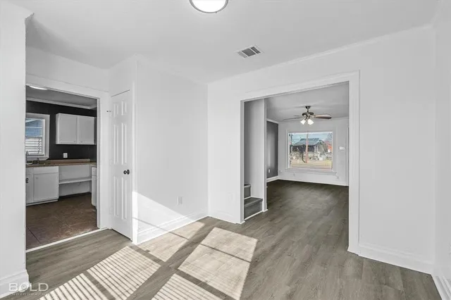 a view of a hallway with wooden floor and a bathroom