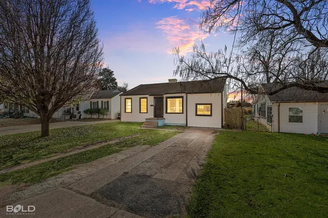 a view of a yard in front of a house with large trees