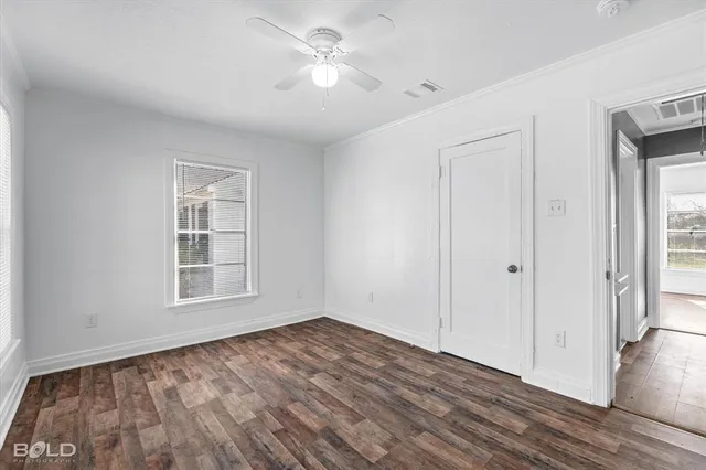 a view of empty room with wooden floor and fan