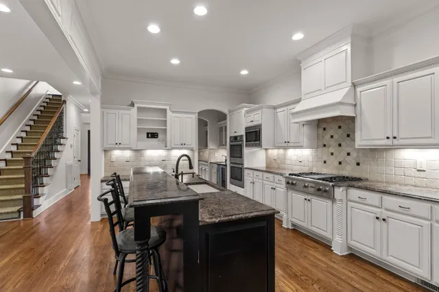 a kitchen with stainless steel appliances granite countertop a stove and a wooden floors