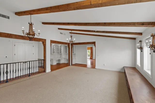 a view of an empty room with wooden floor and window