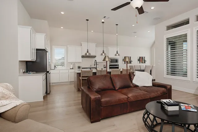 a living room with couches and kitchen view with wooden floor