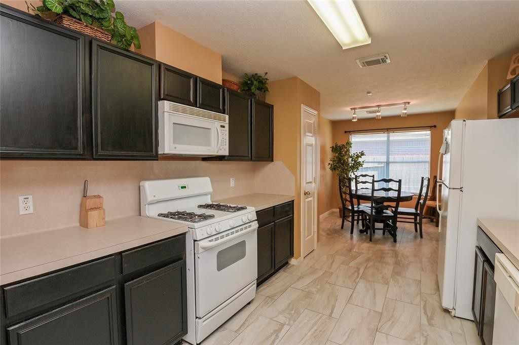 18446 South Wimbledon Drive Katy, TX 77449 - Photo 18 of 24 a kitchen with a stove cabinets and chairs
