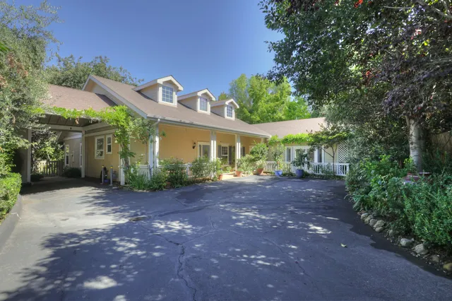 a view of a house with large trees and plants