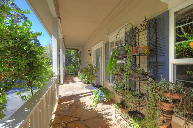 a view of porch with a table and chairs and potted plants