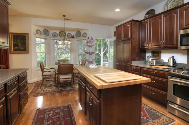 a kitchen with stainless steel appliances granite countertop a refrigerator a stove a sink and a microwave