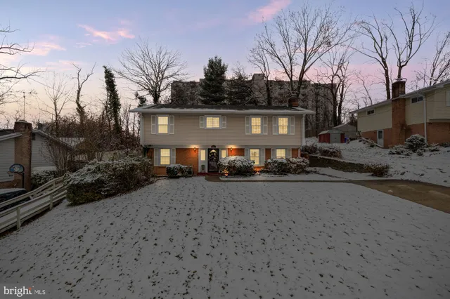 a front view of a house with yard and trees in the background
