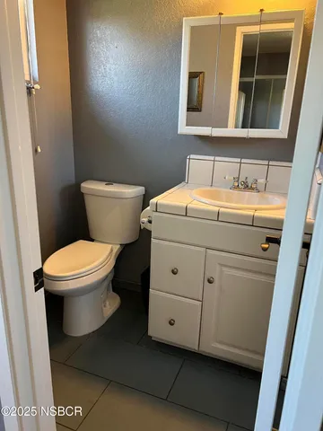a bathroom with a granite countertop toilet sink and mirror