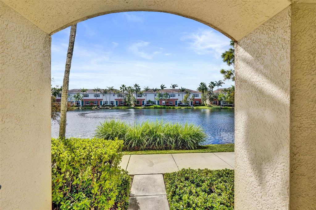 a view of a lake with a floor to ceiling window and potted plants