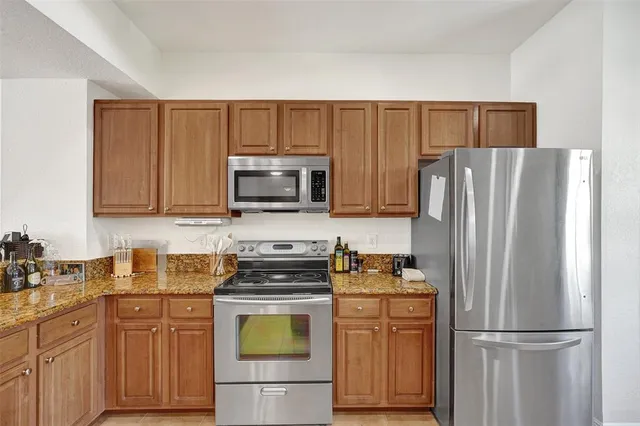 a kitchen with stainless steel appliances granite countertop a refrigerator stove a sink and dishwasher with wooden floor