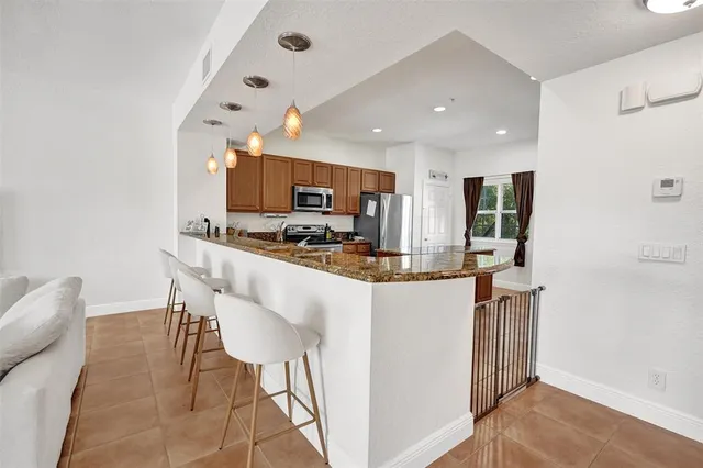 a kitchen with stainless steel appliances kitchen island granite countertop a refrigerator and a stove top oven