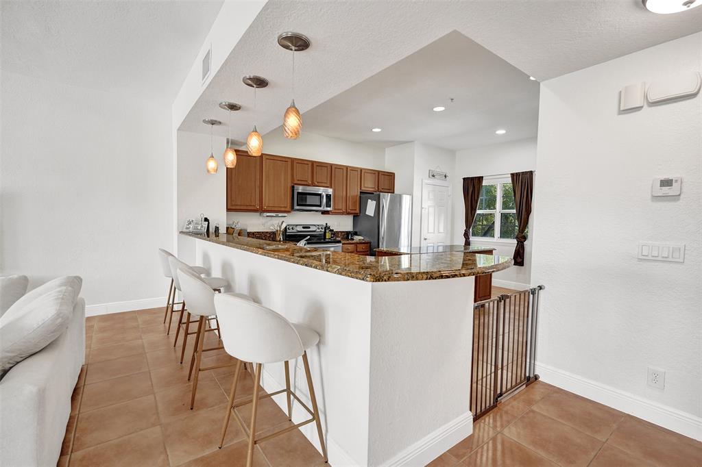 228 Southwest 6th Court Pompano Beach, FL 33060 - Photo 24 of 50 a kitchen with stainless steel appliances kitchen island granite countertop a refrigerator and a stove top oven