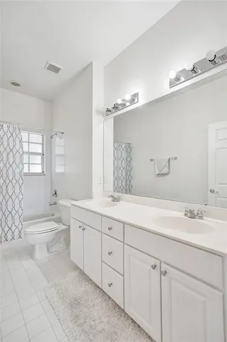 a spacious bathroom with a double vanity sink toilet mirror and bathtub