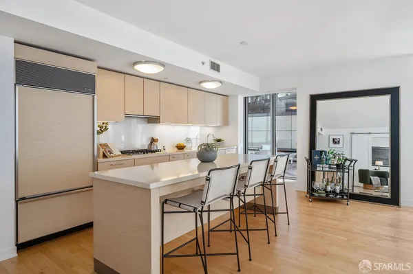 a kitchen with stainless steel appliances granite countertop a stove a refrigerator a sink a dining table and chairs with wooden floor