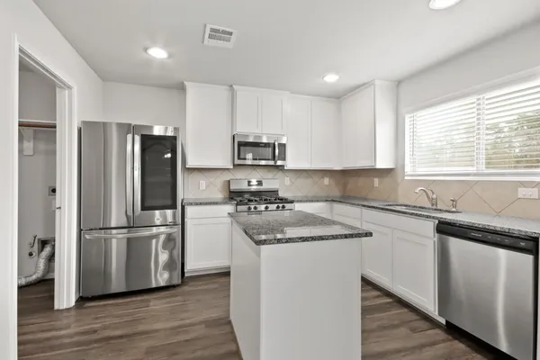 a kitchen with granite countertop a sink stove and microwave