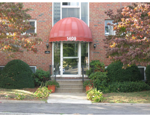a view of a brick building with a yard and large tree