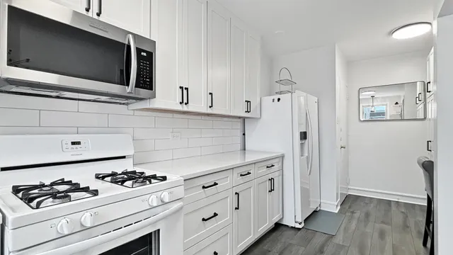 a kitchen with white cabinets and appliances