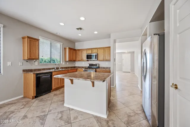 a kitchen with stainless steel appliances granite countertop a refrigerator and a stove top oven