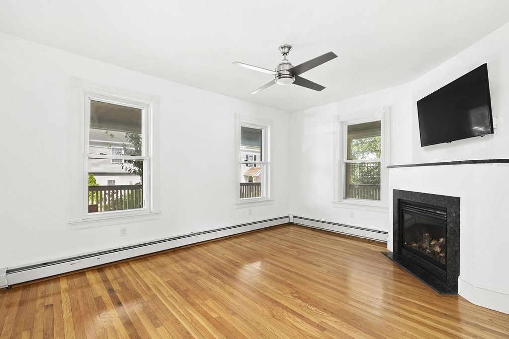 53 Prospect Avenue Winthrop, MA 02152 - Photo 3 of 18 a view of an empty room with wooden floor a fireplace and a window