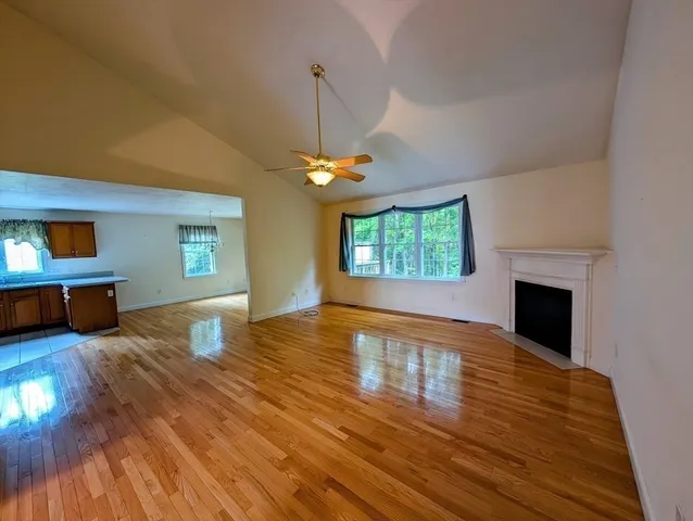 a view of a livingroom with wooden floor fireplace and a window