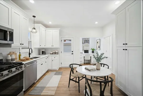 a kitchen with stainless steel appliances kitchen island granite countertop a stove a sink a refrigerator a dining table and chairs