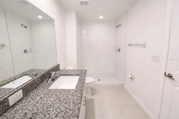 a bathroom with a granite countertop sink a toilet and shower