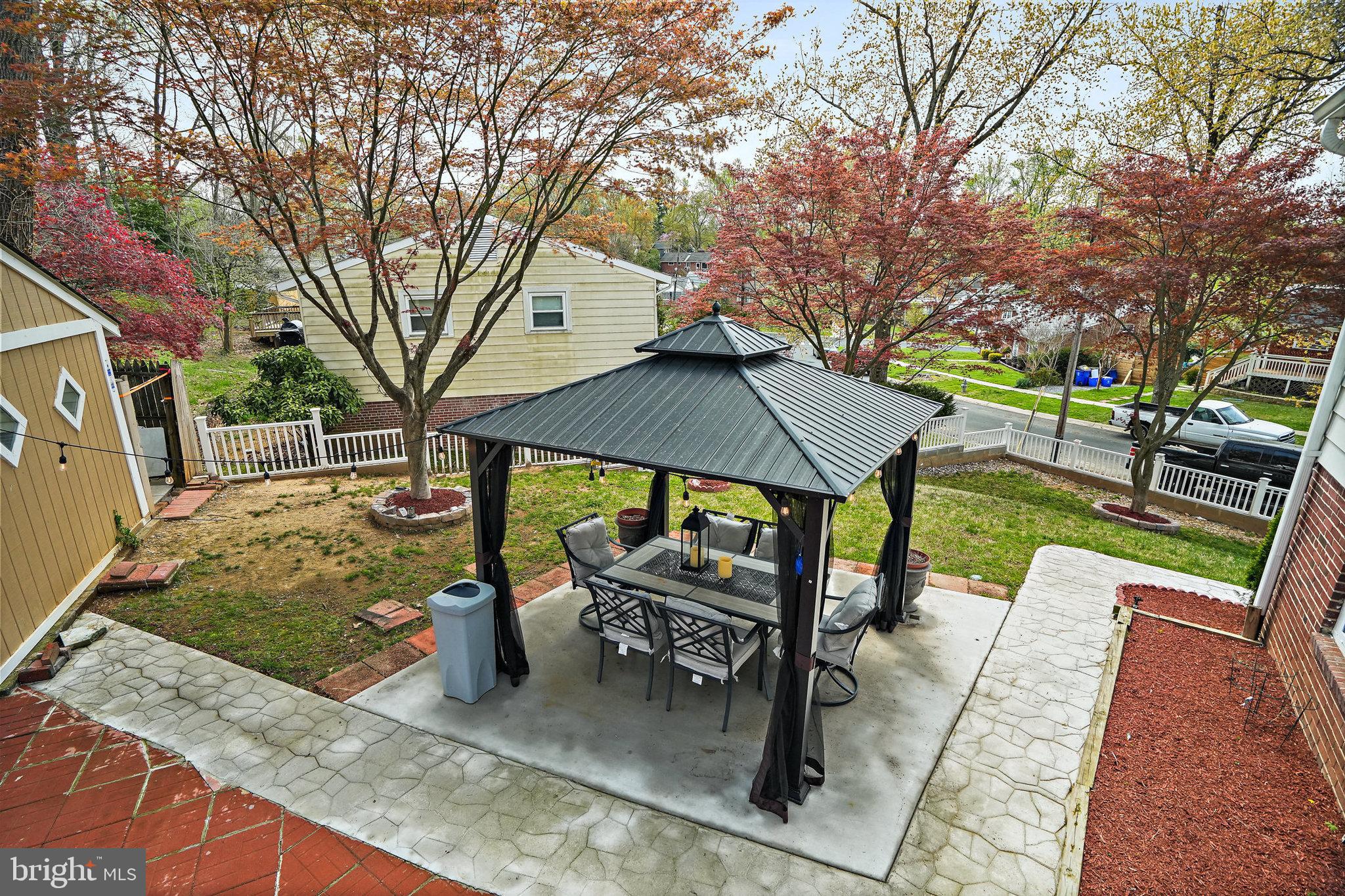3816 Kayson Street Silver Spring, MD 20906 - Photo 39 of 44 a view of a patio with table and chairs under an umbrella with large trees