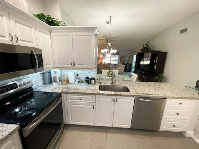 a kitchen with stainless steel appliances kitchen island granite countertop a refrigerator and a sink