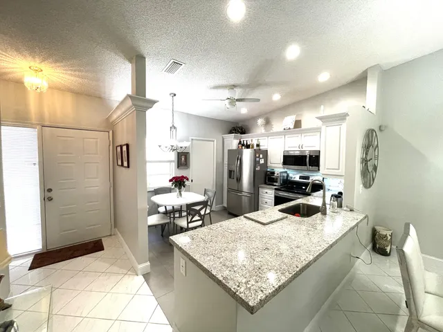 a kitchen with stainless steel appliances kitchen island granite countertop a sink refrigerator and microwave