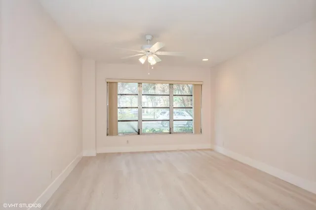 an empty room with chandelier fan and windows