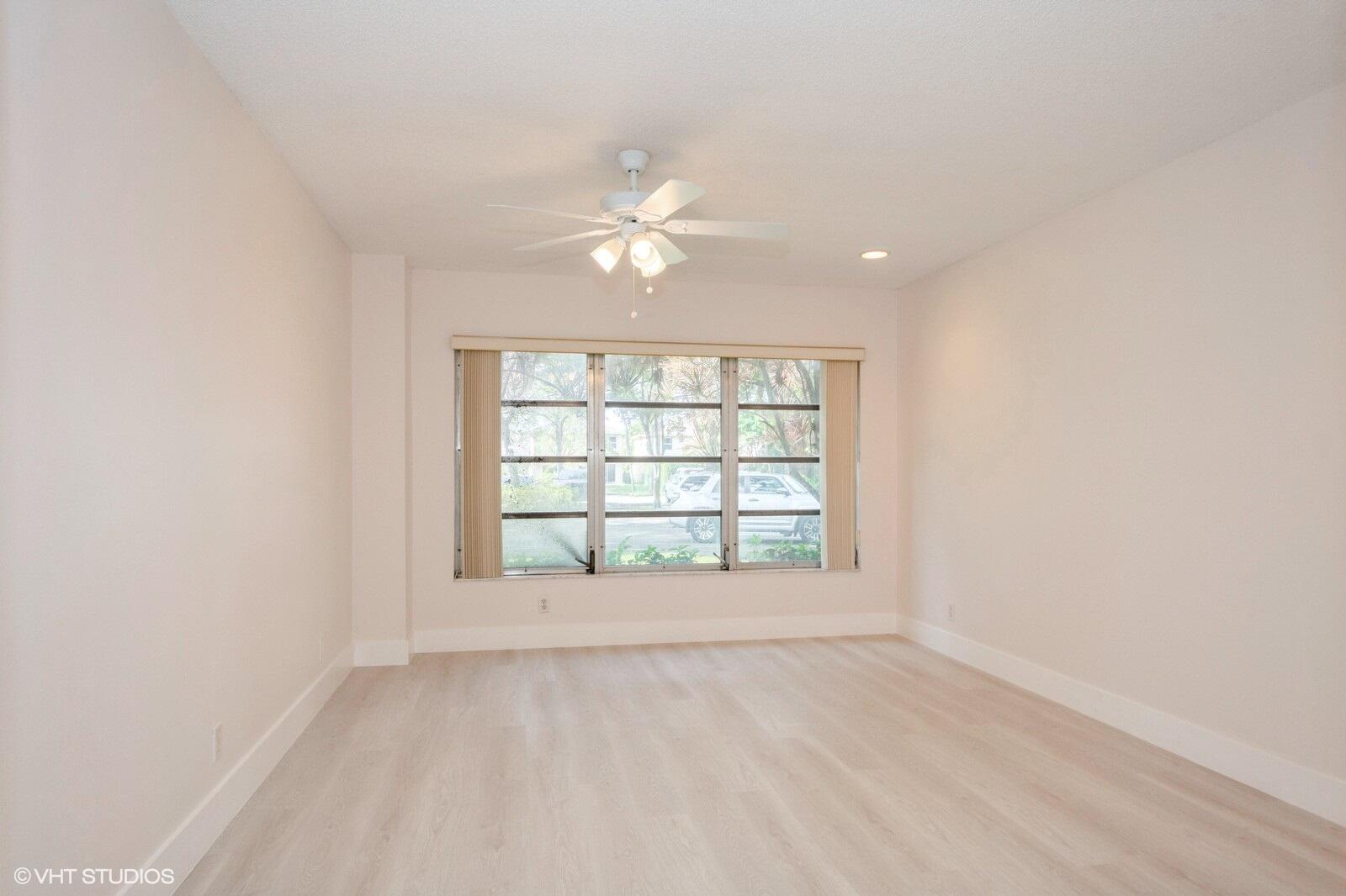 10777 West Sample Road, Unit 101 Coral Springs, FL 33065 - Photo 16 of 36 an empty room with chandelier fan and windows