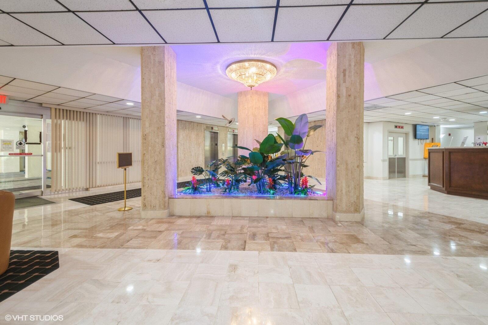 10777 West Sample Road, Unit 101 Coral Springs, FL 33065 - Photo 2 of 36 a view of a hallway with a dining table and chairs