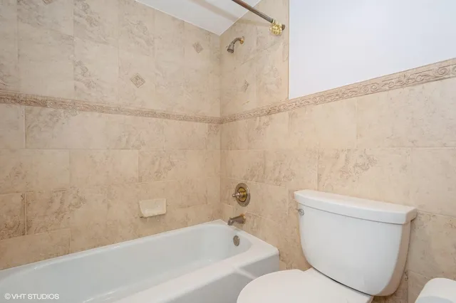 a white toilet sitting next to a bath tub and a shower