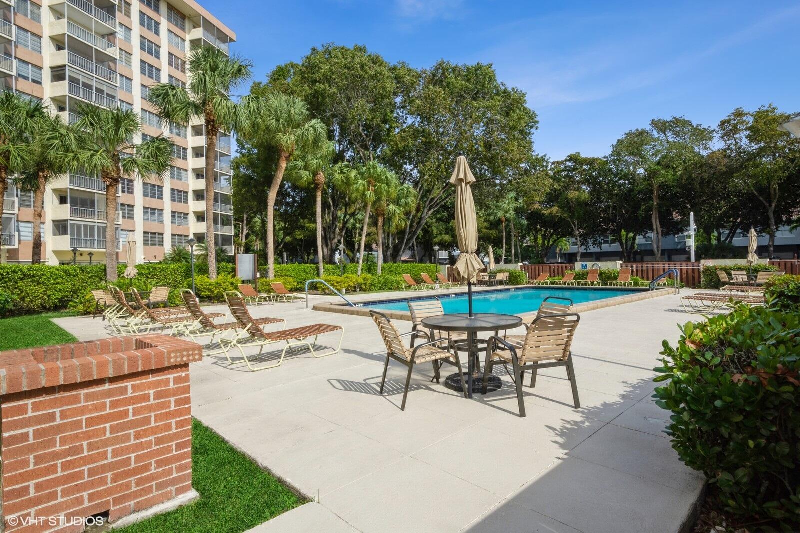 10777 West Sample Road, Unit 101 Coral Springs, FL 33065 - Photo 30 of 36 a swimming pool with outdoor seating and yard