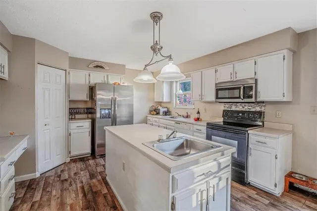 a kitchen with a sink a stove a refrigerator and cabinetry
