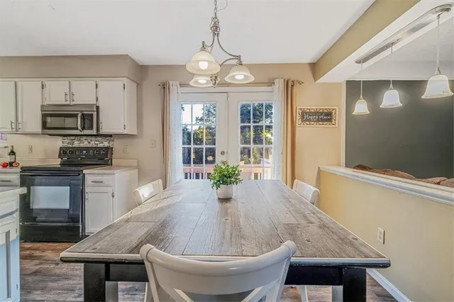 a kitchen with stainless steel appliances granite countertop a stove a refrigerator a microwave oven with a dining table and chairs