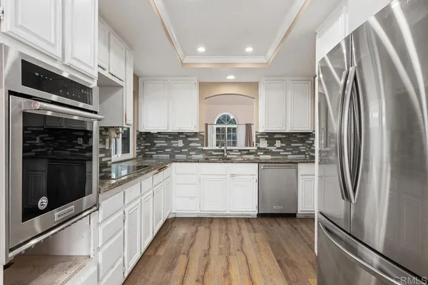 a kitchen with white cabinets and appliances