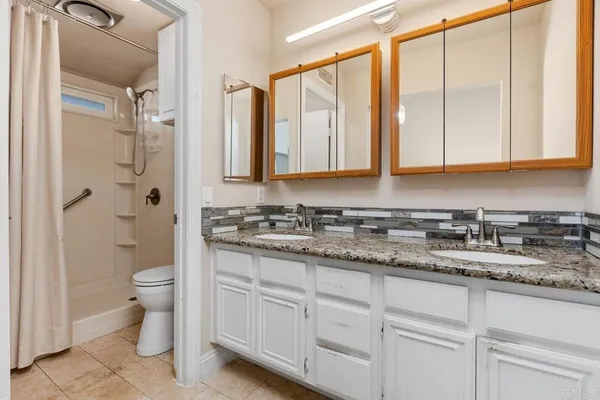 a bathroom with a granite countertop toilet sink and mirror