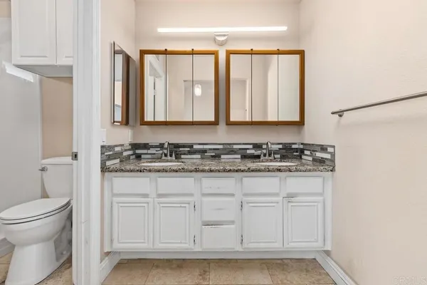 a bathroom with a granite countertop sink and a toilet