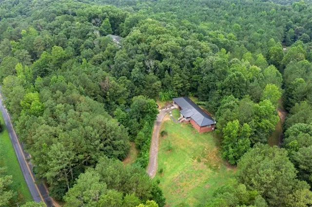 an aerial view of residential house with outdoor space and trees all around