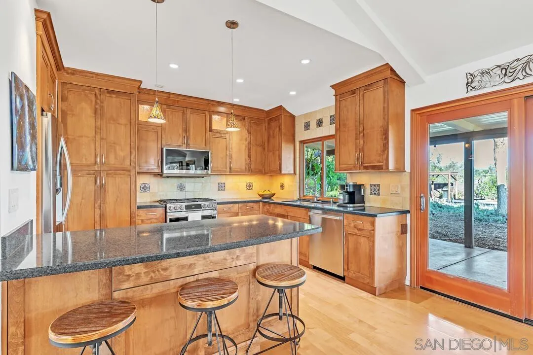 290 North Old Hill Road Fallbrook, CA 92028 - Photo 9 of 47 a kitchen with stainless steel appliances granite countertop a stove a sink and a refrigerator with wooden floor